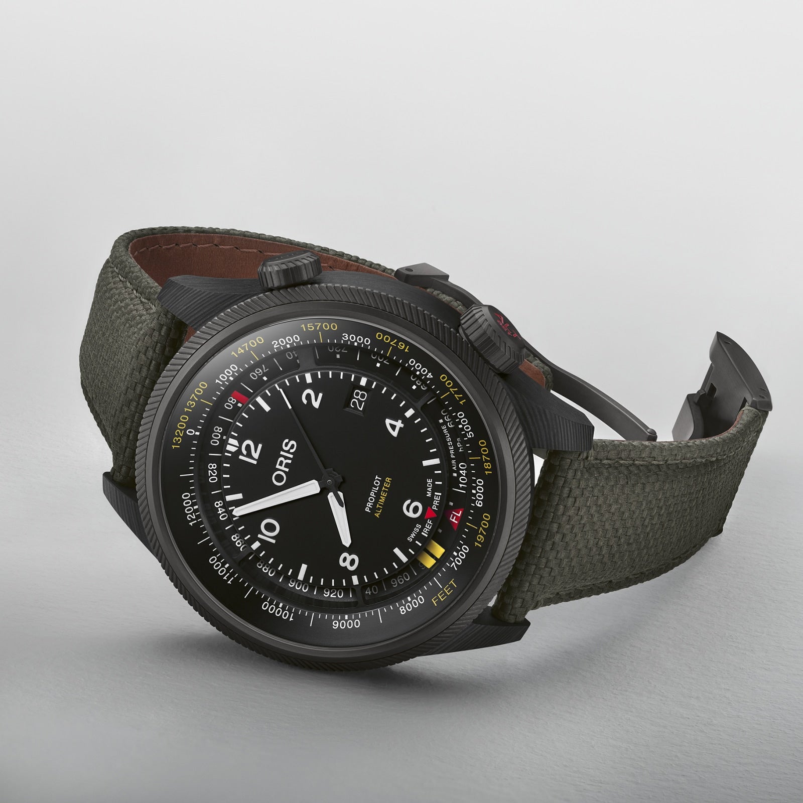 An Oris ProPilot Altimeter wristwatch featuring a black case, fabric strap, white numerals, multi-scale dial, and dual crowns with integrated altimeter module, displayed on a white surface.