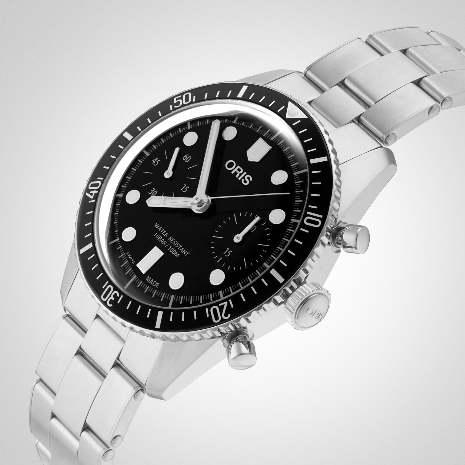 The Oris Divers Sixty‑Five Chronograph, featuring a stainless steel case with black dial and bezel, is pictured on a light gradient background.