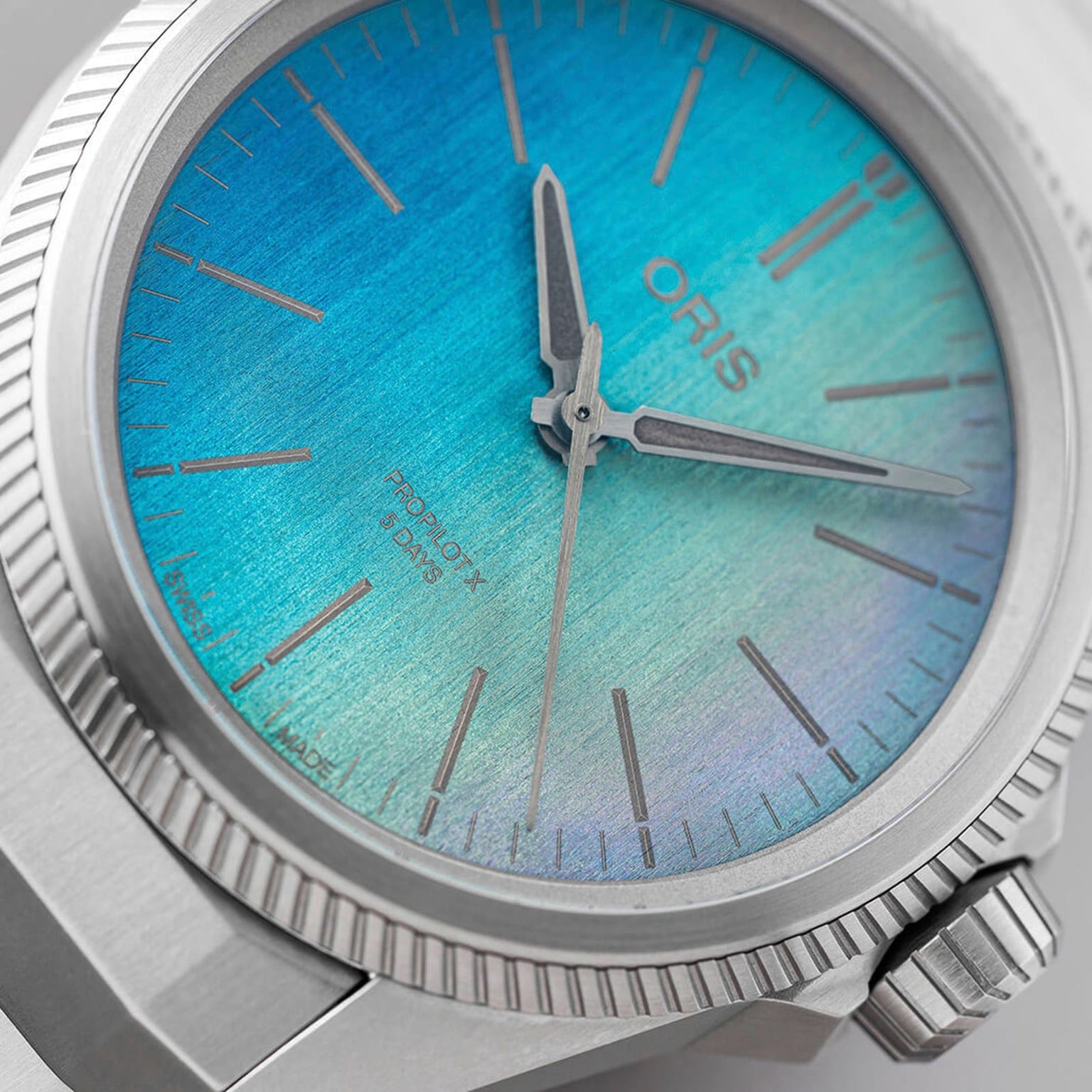 Close-up of the Oris ProPilot X Calibre 400 Laser wristwatch featuring a gradient blue and green dial, silver hands, and a serrated bezel.