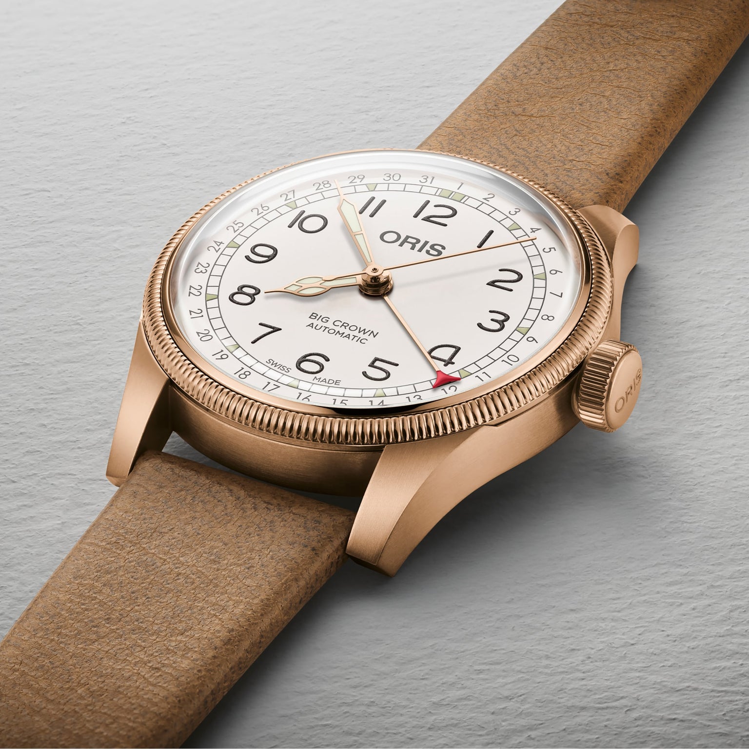 The Oris Big Crown Father Time Limited Edition, known for its reliable mechanical movement, features a white dial, black numerals, brown leather strap, and red-tipped date hand, shown resting on a light grey surface.