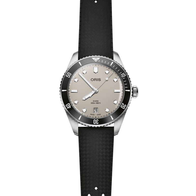 The Oris Divers Date wristwatch features automatic movement, a beige dial, black bezel, white markers, date window at 6 o’clock, and a textured black rubber strap, all in stainless steel and shown on a white background.