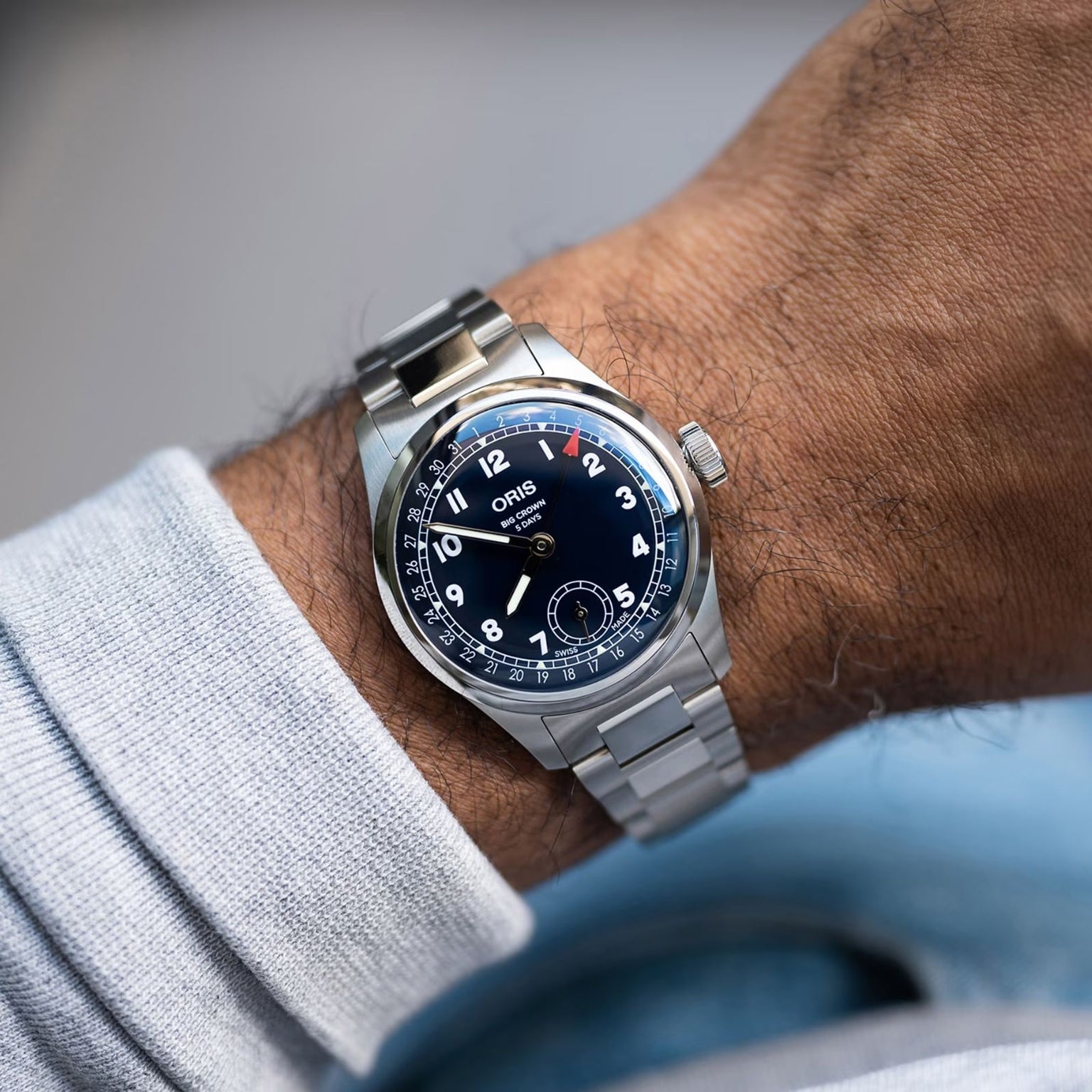 An Oris Big Crown Pointer Date Calibre 403 with a stainless steel case, midnight blue dial, Arabic numerals, and metal bracelet is worn on a persons left wrist.