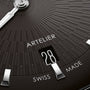 Black dial watch face with radial line pattern, showing date window at 28, Artelier branding, and Swiss Made text, with silve