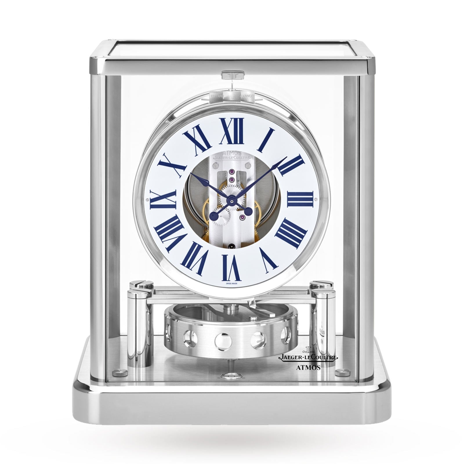 The Jaeger-LeCoultre Atmos Classique features a glass case, white dial with blue Roman numerals, visible internal mechanisms, and a sleek silver base for modern elegance.