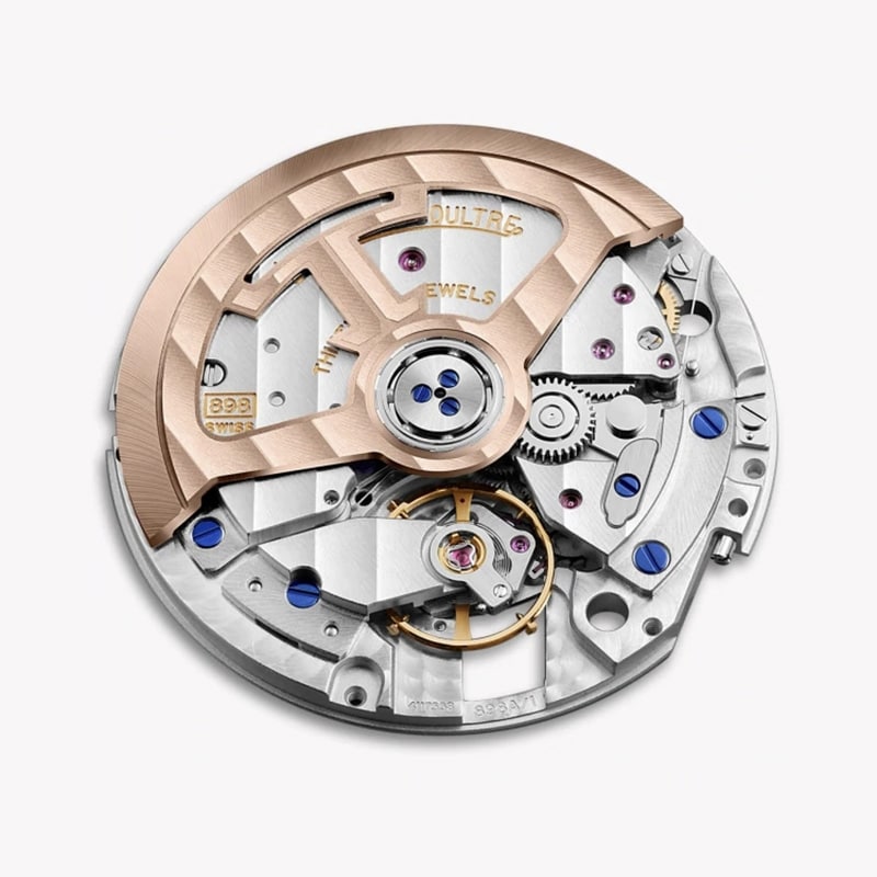 Close-up of the Jaeger-LeCoultre Rendez-Vous Night & Day watch movement, showcasing a rose gold rotor, silver gears, blue screws, and visible jewels arranged with luxurious craftsmanship.