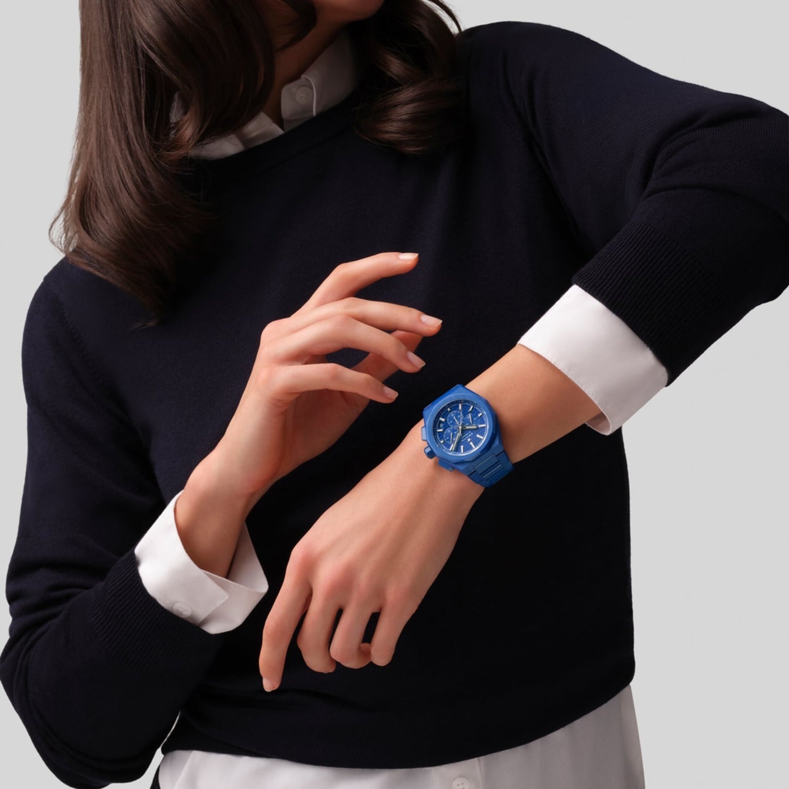 A person in a black sweater with white cuffs adjusts a Zenith Limited Edition Defy Skyline Chronograph 160th Anniversary Edition on their left wrist, highlighting its exclusive elegance against a simple light background.