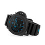 A Panerai Submersible Carbotech divers watch with a carbon fibre case, black rubber strap, black dial, and bright blue markers and hands is displayed at an angle on a white background.