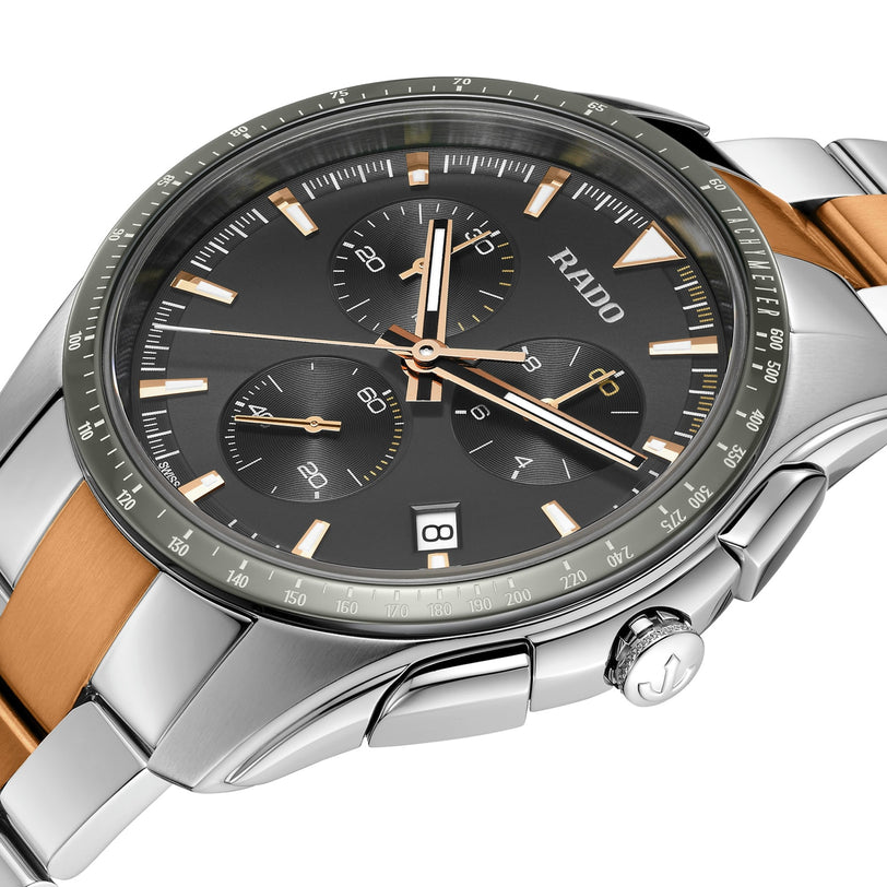 Close-up of the Rado Hyperchrome Chronograph featuring a black dial, silver and gold accents, three subdials, date display, and a two-tone bracelet crafted from high-tech ceramic.