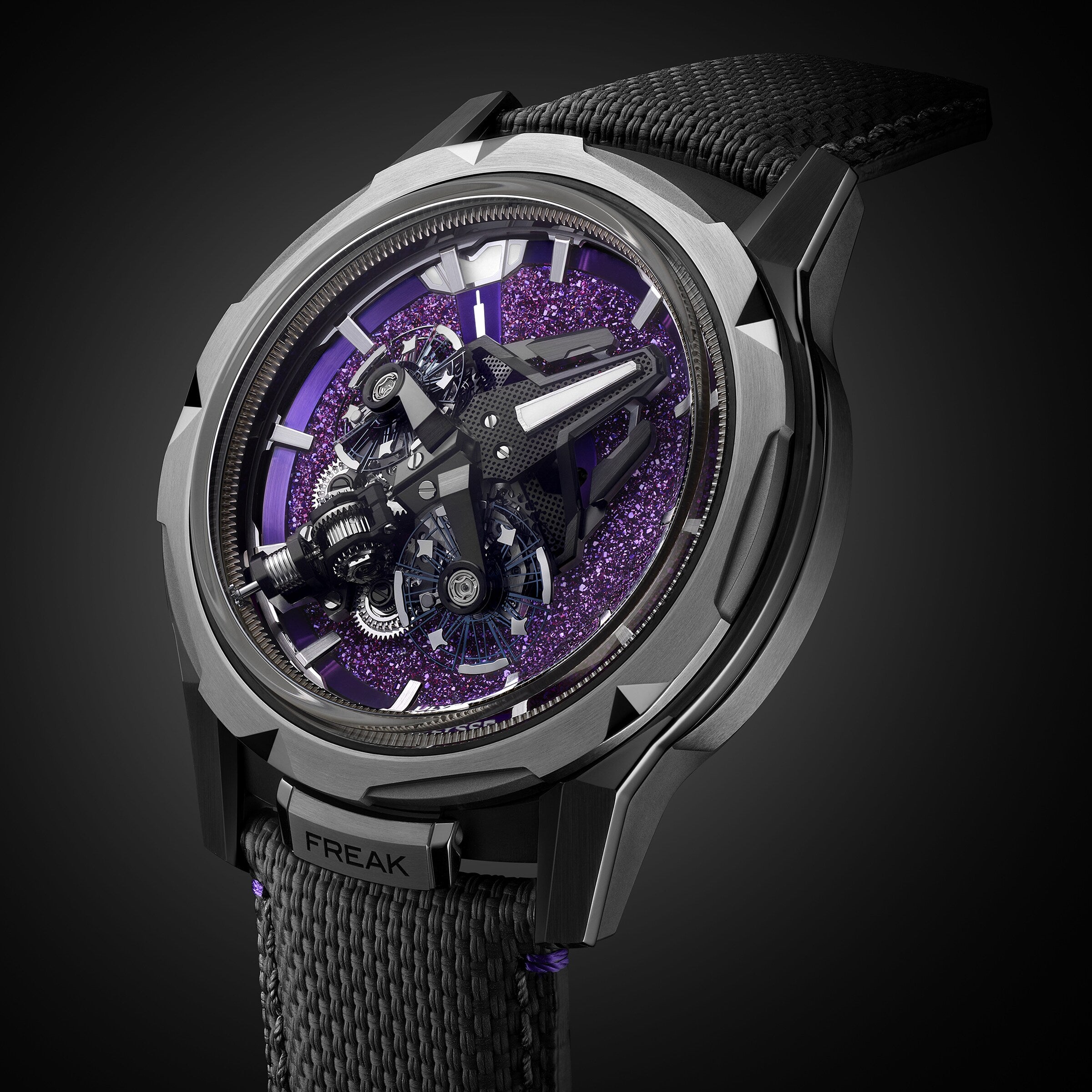 A close-up of the Ulysse Nardin Freak S WOS Centenary Exclusive, featuring its detailed exposed mechanical movement and black strap, set against a purple textured background signature to the brand.