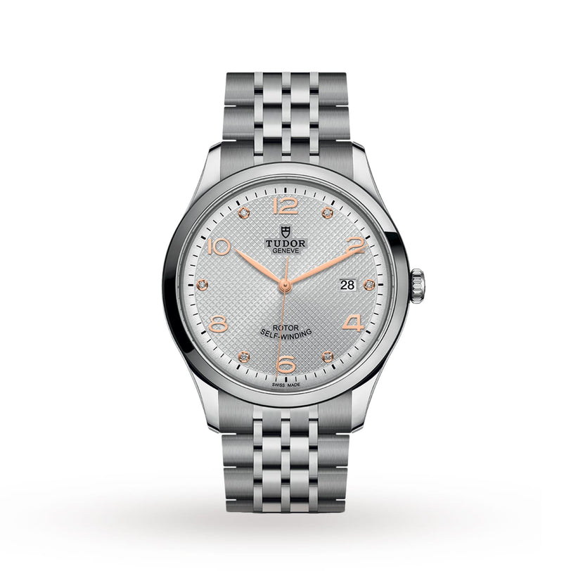 The TUDOR 1926 wristwatch features a silver metal bracelet, silver textured dial, gold-tone markers and hands, self-winding movement, and a date display at 3 o’clock.