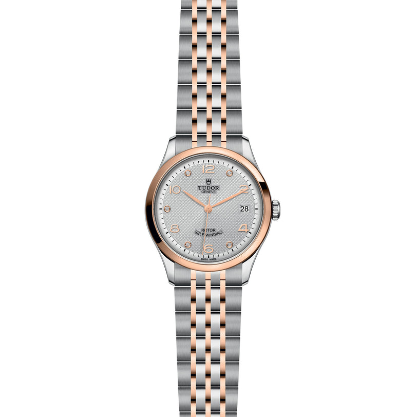 The TUDOR 1926 wristwatch features a silver and rose gold metal link bracelet, white textured dial, date display, gold hour markers, and a scratch-resistant sapphire crystal lens.