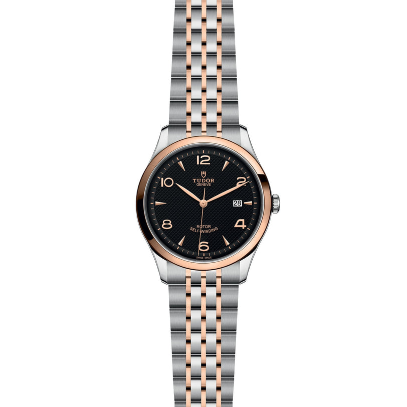 The TUDOR 1926 wristwatch features a round black dial, gold-tone markers and hands, a date display, and a two-tone silver and rose gold bracelet—an elegant nod to TUDOR’s tradition in fine mechanical watches.