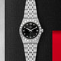 A TUDOR Royal wristwatch with a black dial, Roman numerals, diamond markers, date window, and integrated bracelet is displayed against a textured black and metallic backdrop.