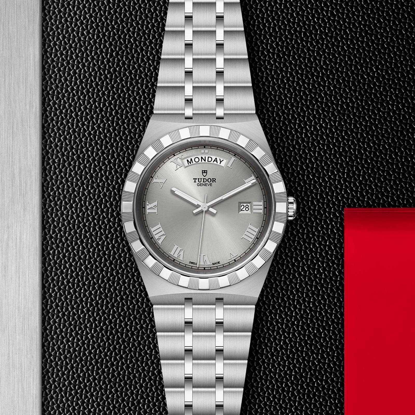 A TUDOR Royal wristwatch with day and date display, Roman numerals, and an integrated bracelet is presented on a textured black and metallic background, reflecting the elegance of automatic sport-chic timepieces.