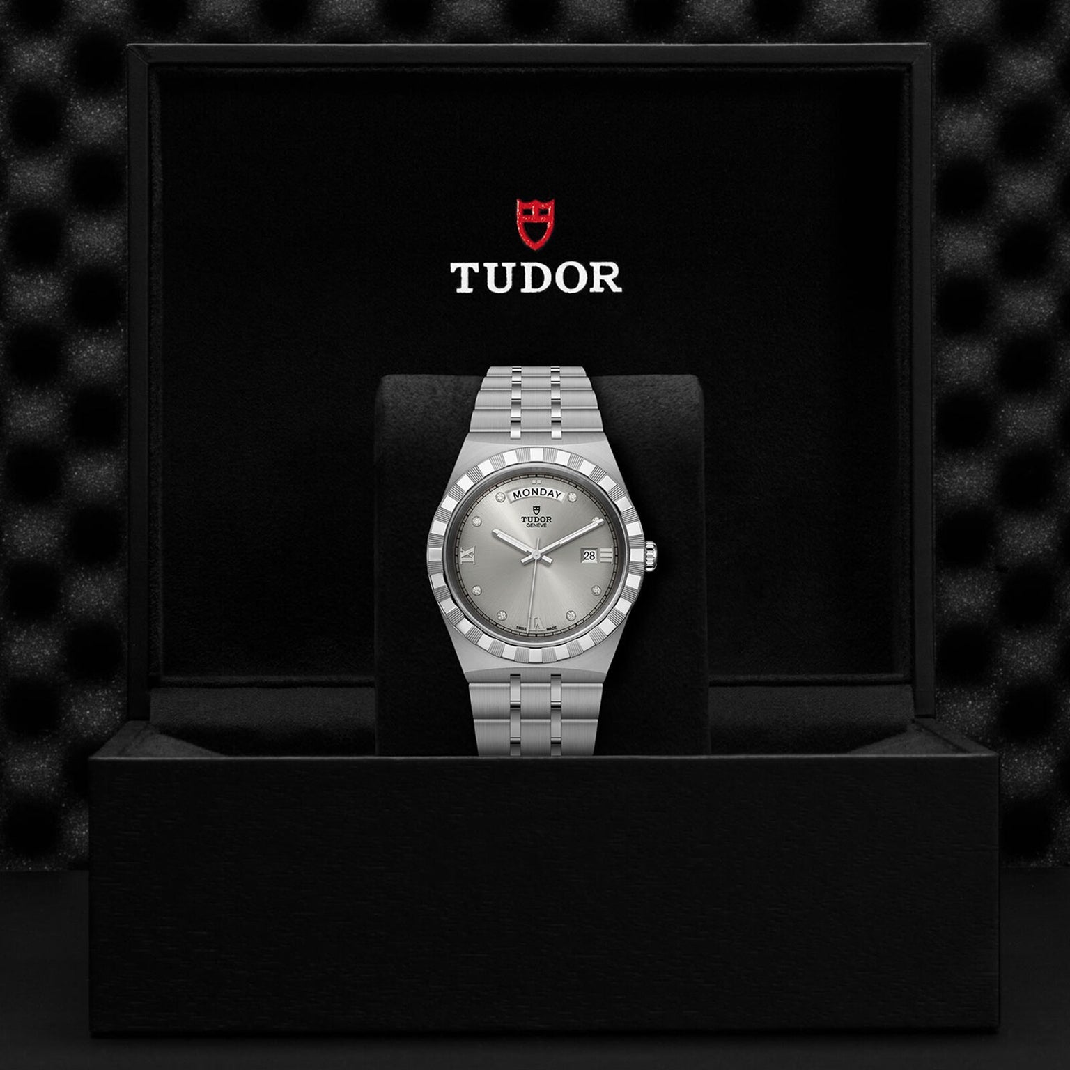 A TUDOR Royal wristwatch with an integrated bracelet is displayed in an open black box bearing the TUDOR logo on the inside lid—a refined example of TUDOR’s automatic sport-chic timepieces.