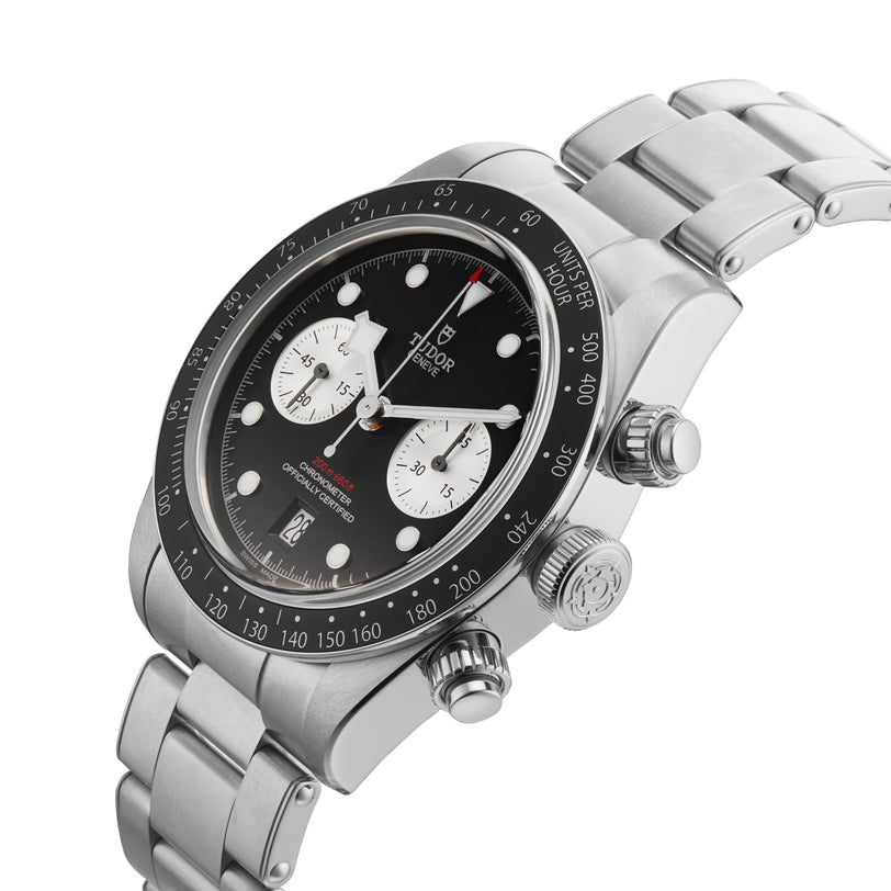 A TUDOR Black Bay Chrono wristwatch featuring a black bezel with tachymetric scale, black dial with two white subdials, and metal bracelet—shown at an angle.