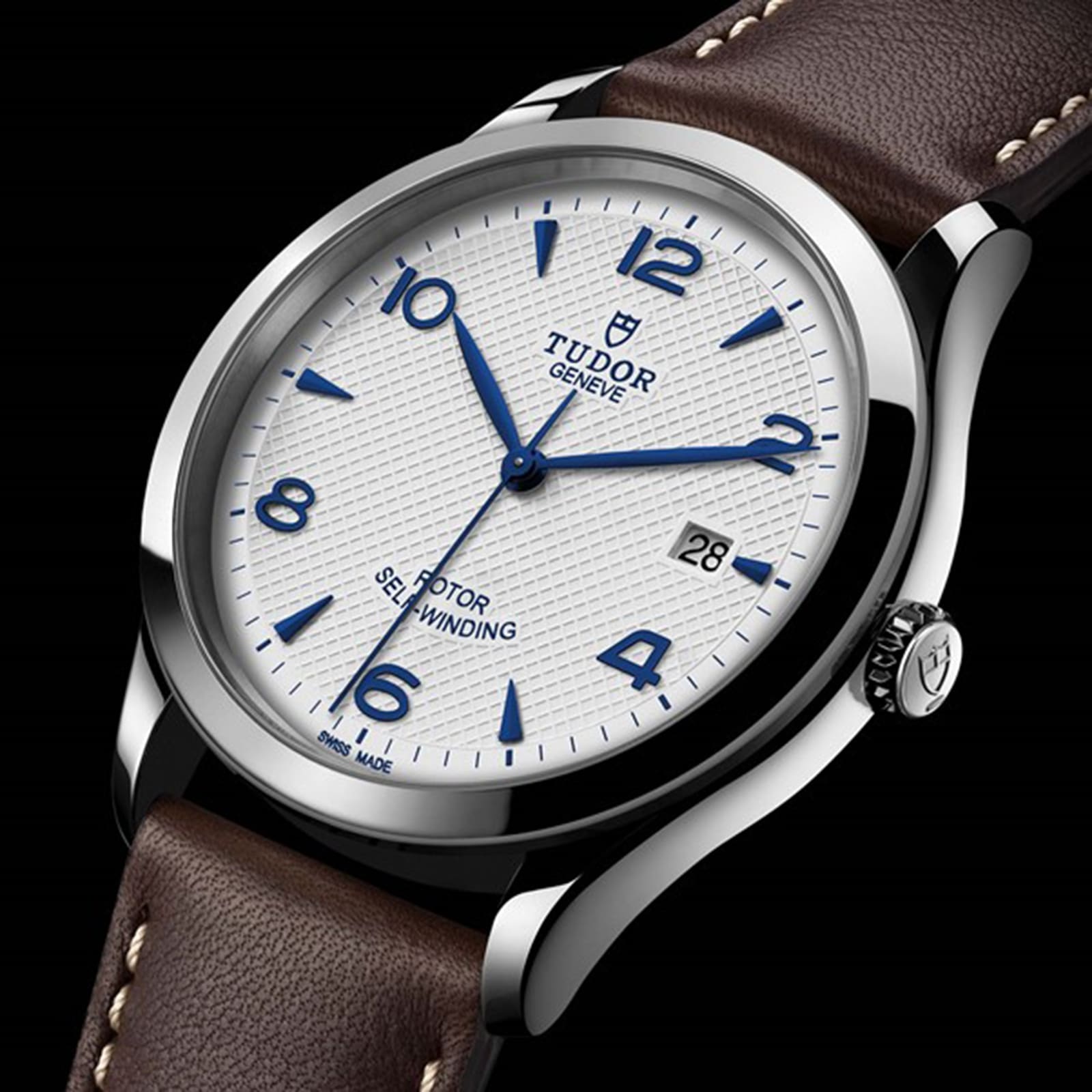 The TUDOR 1926 wristwatch features a textured opaline dial with blue numerals and hands, date at 3 oclock, a brown leather strap, and stainless steel case—a timeless pick for mechanical watch enthusiasts.