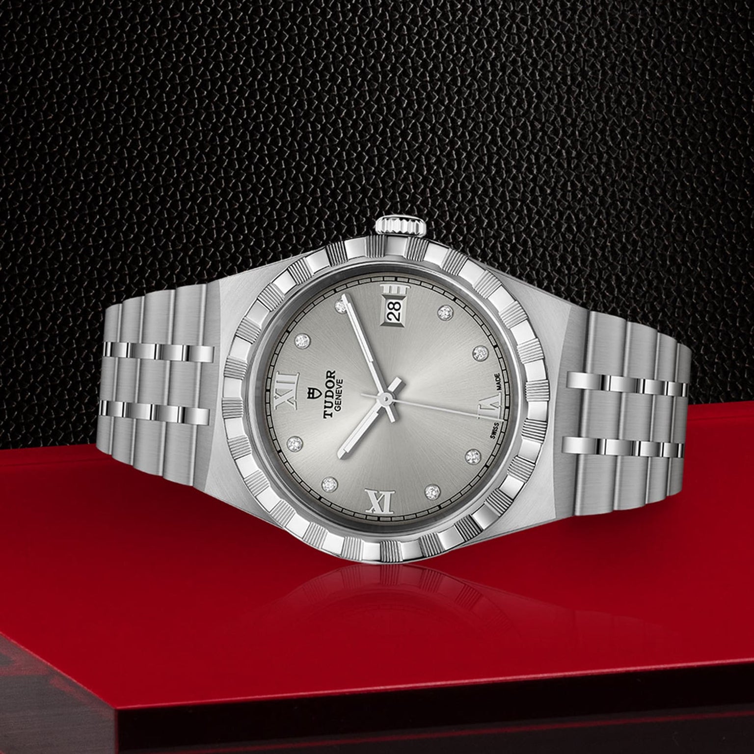 The TUDOR Royal watch sideways on a red table with a black background