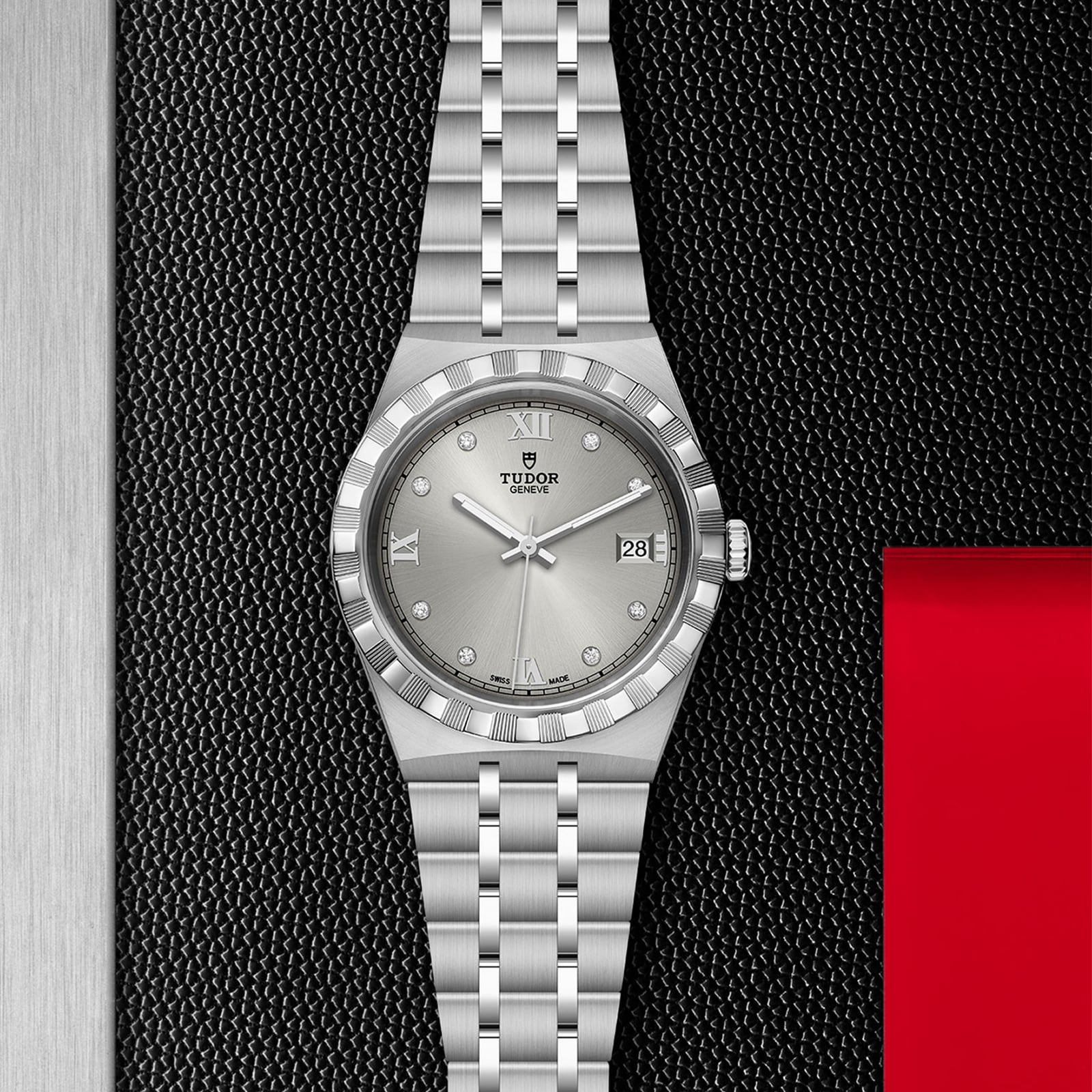 A TUDOR Royal wristwatch with integrated bracelet, green dial, diamond markers, and date display is photographed on a textured black and metal background with a red accent.