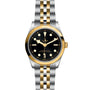 The TUDOR Black Bay One 36 S&G is a two-tone wristwatch featuring a black dial, gold hour markers, gold bezel, and a stainless steel and gold bracelet. The time on the watch is set to 10:10.