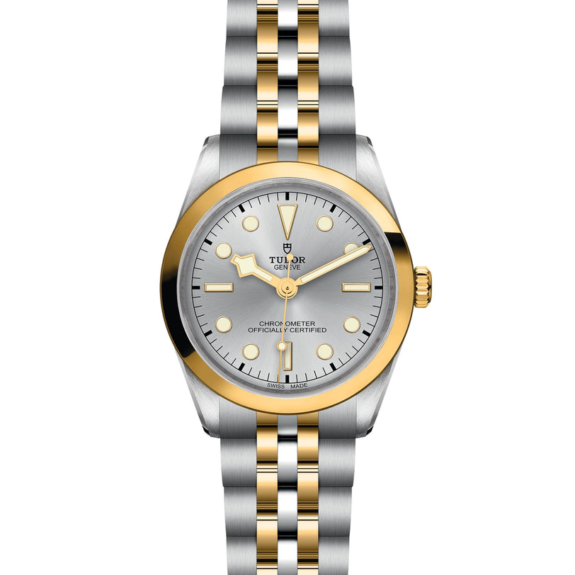 The TUDOR Black Bay One 36 S&G is a two-tone wristwatch with a silver dial, gold bezel, gold and silver bracelet, date window, and is chronometer officially certified.
