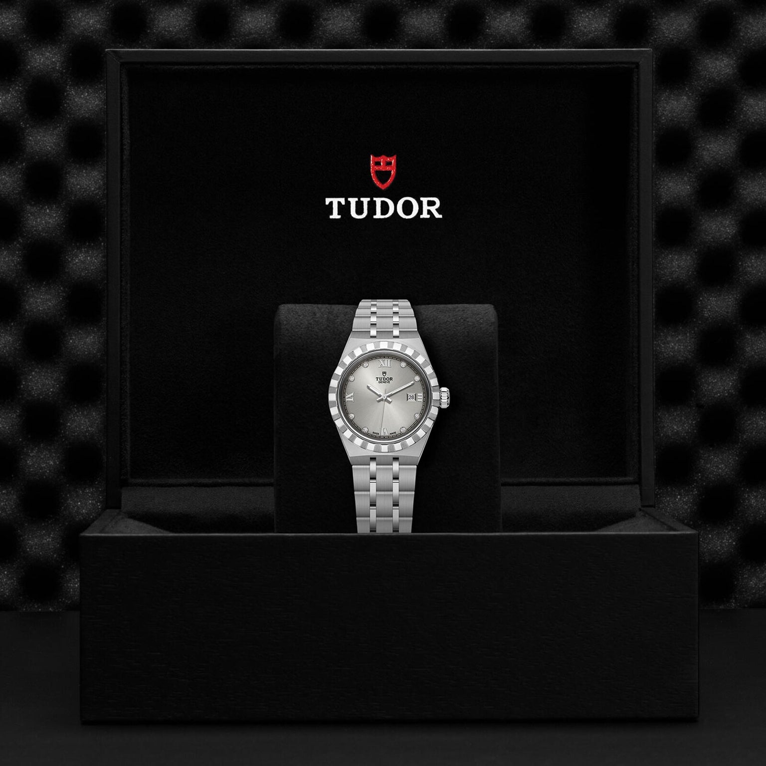 A TUDOR Royal sport-chic automatic watch with a silver and gold band is displayed upright in a black presentation box featuring the Tudor logo and emblem above it.