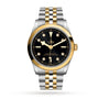 The TUDOR Black Bay One 36 S&G wristwatch features a black dial, gold hour markers, a steel and gold bracelet, and a gold bezel, shown against a white background.
