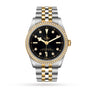 The TUDOR Black Bay One 36 S&G wristwatch features a black dial, diamond-set yellow gold bezel, and a two-tone silver and yellow gold bracelet.