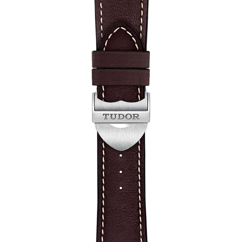 Close-up of a brown leather strap with white stitching and a silver clasp engraved with TUDOR, exemplifying the refined craftsmanship of the TUDOR 1926 collection.