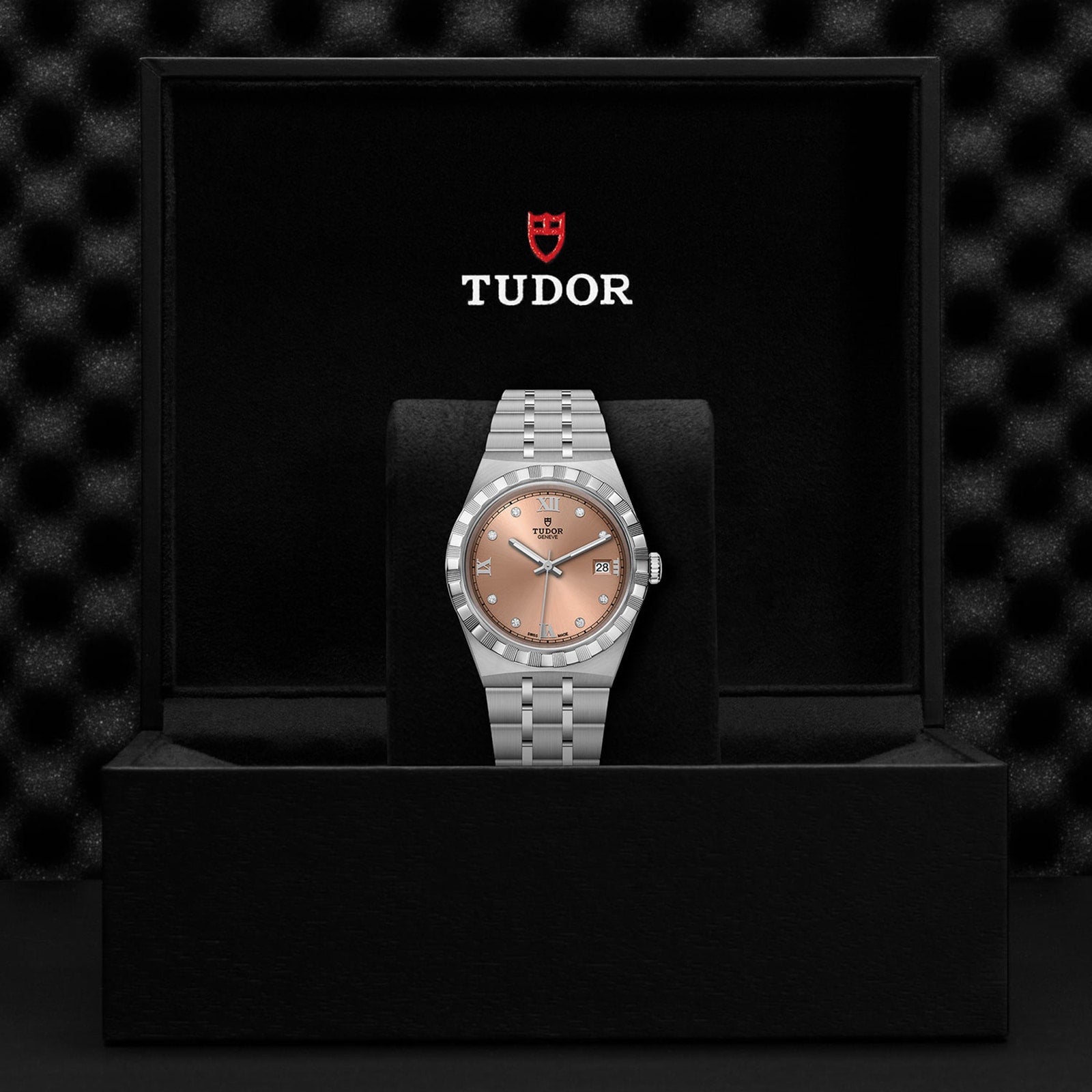 A TUDOR Royal wristwatch with a silver case and salmon dial displayed in an open black TUDOR box.