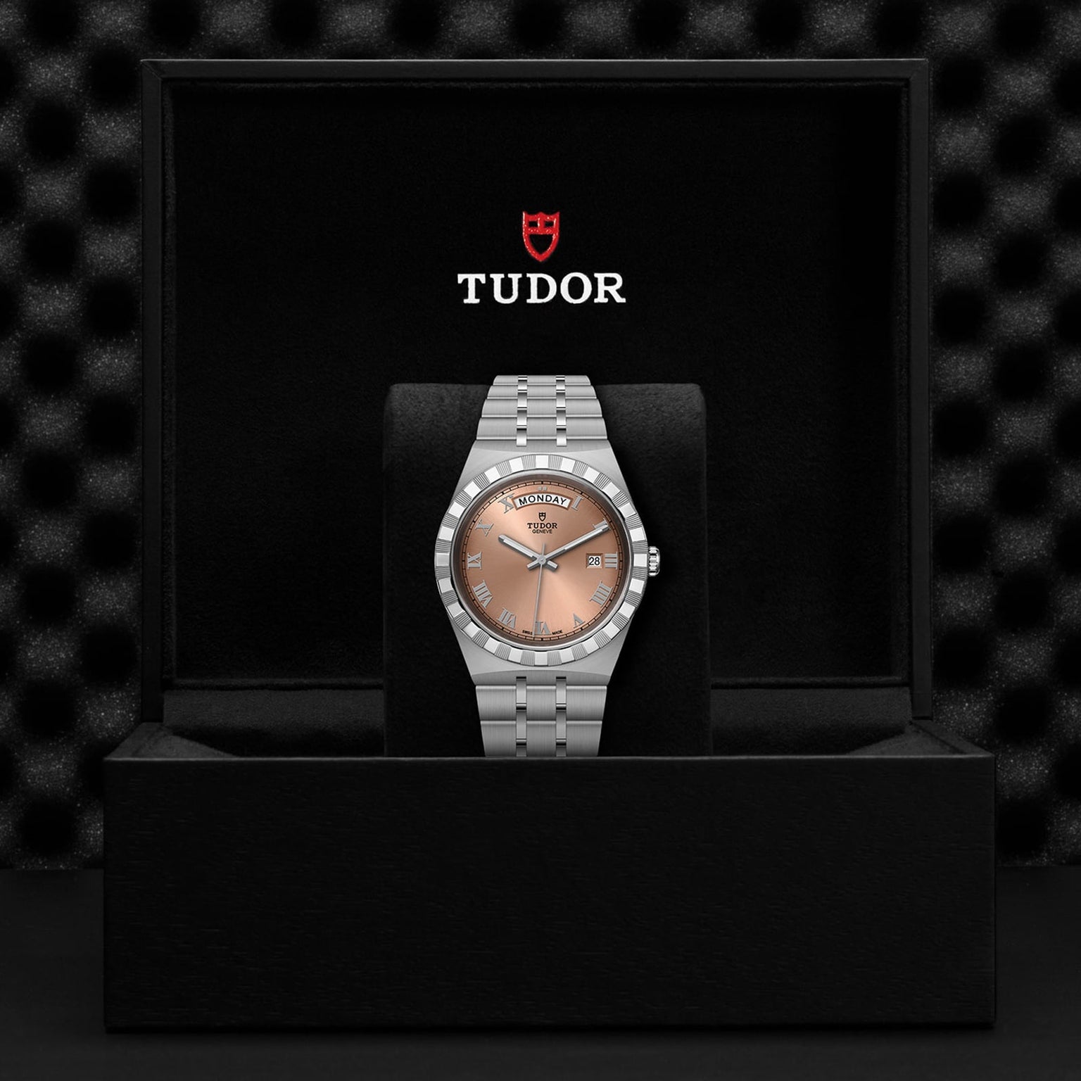 The TUDOR Royal wristwatch features a silver band and salmon dial with automatic movement, presented in a black Tudor-logo box.