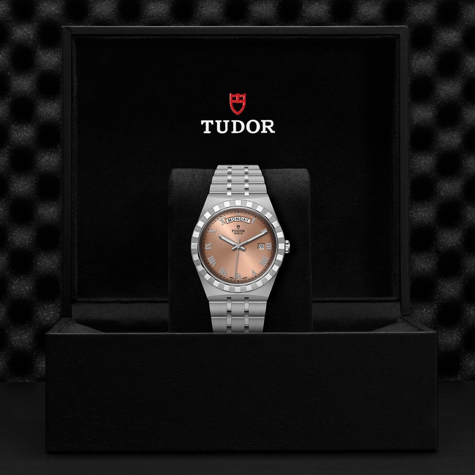 The TUDOR Royal wristwatch features a silver band and salmon dial with automatic movement, presented in a black Tudor-logo box.
