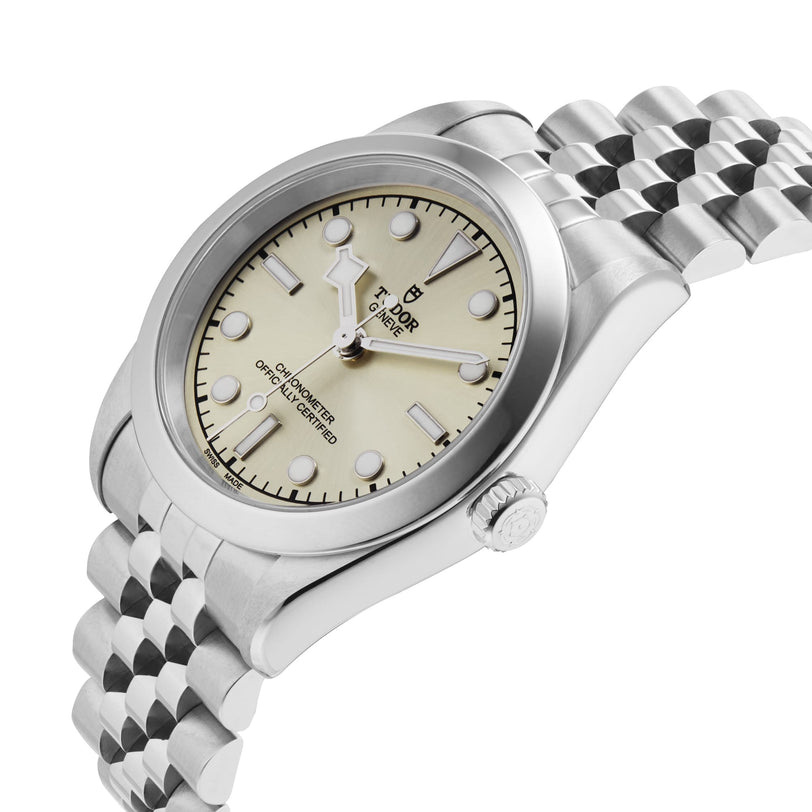 The TUDOR Black Bay One 31, a stainless steel unisex wristwatch with a cream dial, round markers, and jubilee-style bracelet, delivers chic style in a design reminiscent of classic Black Bay models and is displayed at an angle.