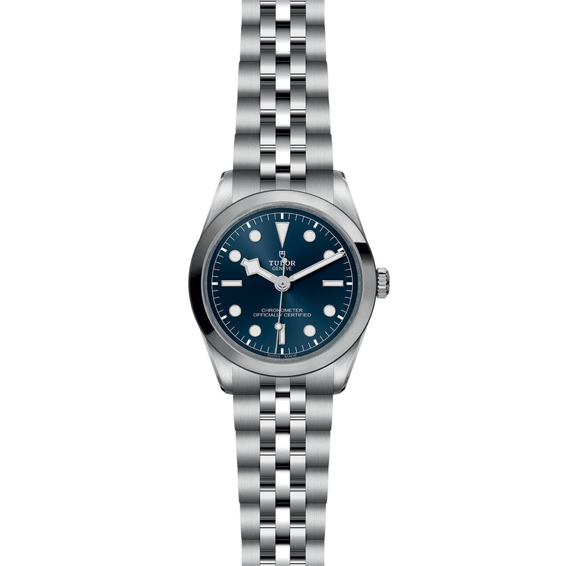 The TUDOR Black Bay One 36 unisex watch features a blue dial, white hour markers, and a silver jubilee-style bracelet, inspired by Black Bay models and displayed against a white background.