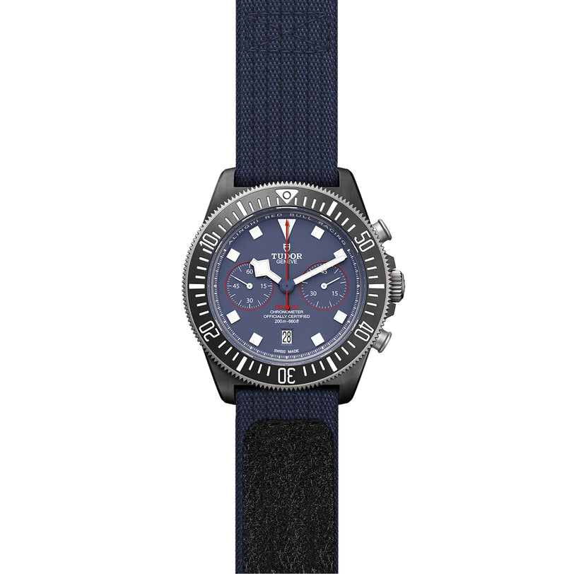 The TUDOR Pelagos FXD Chrono is a blue wristwatch inspired by the French Navy, with a chronograph dial, white markers, three subdials, date window, black rotating bezel, and blue fabric strap—ideal for underwater navigation.