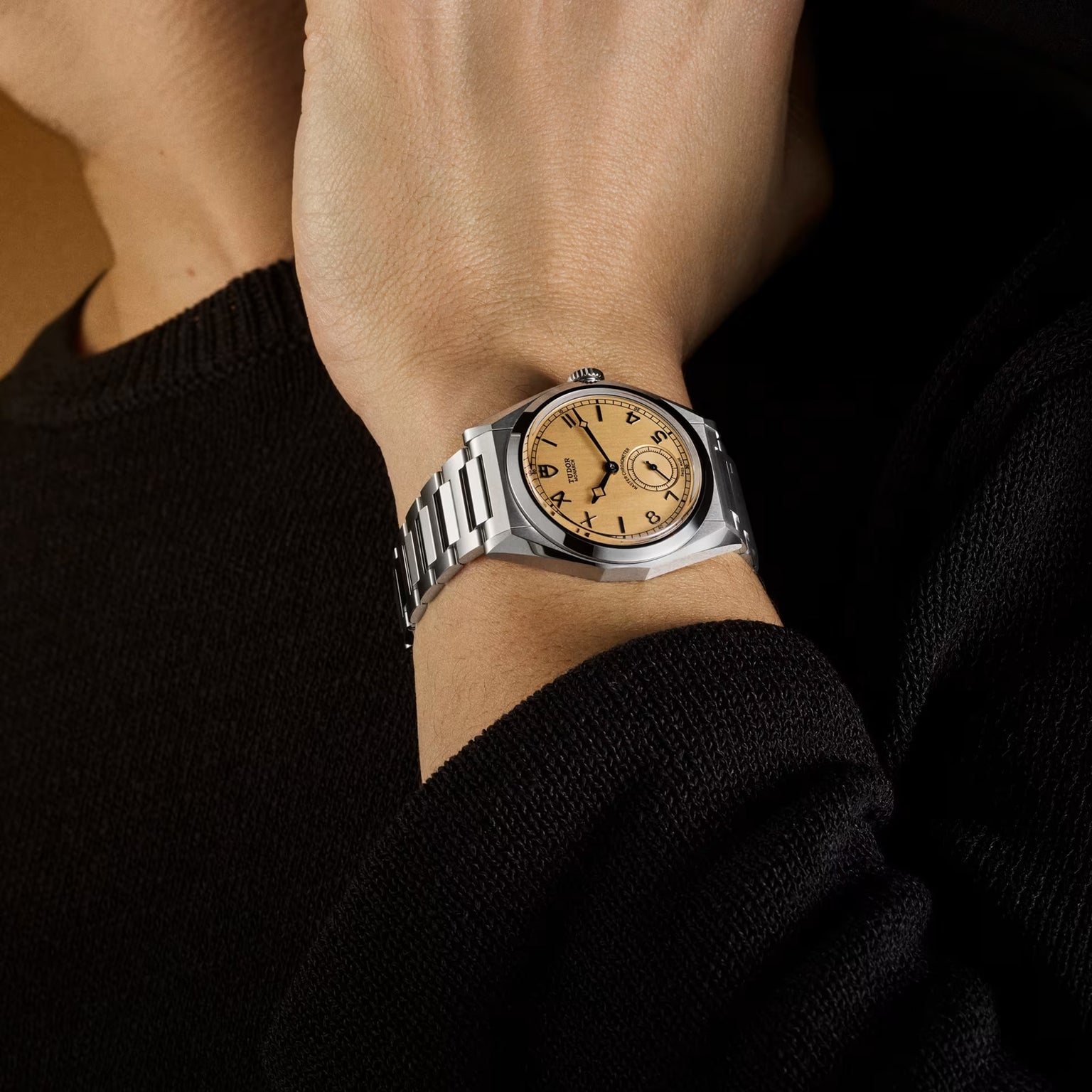 TUDOR Monarch watch with cream dial and stainless steel bracelet worn on wrist.