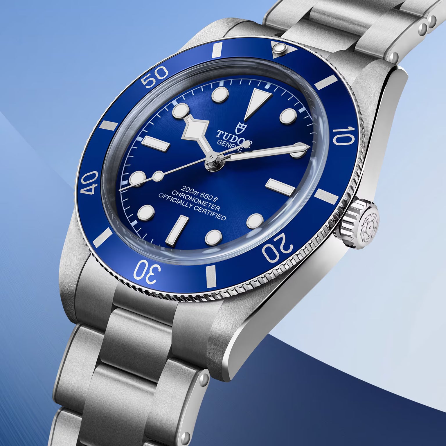 Stainless steel watch with blue dial, blue bezel, white hour markers, and metal bracelet band.