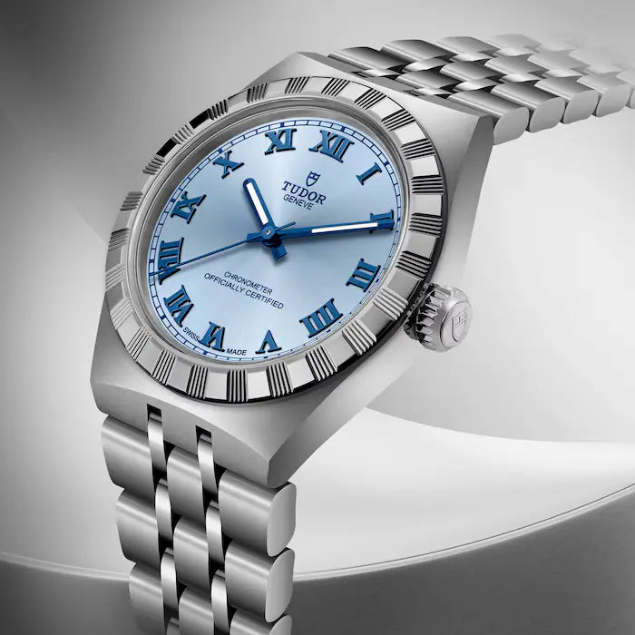 TUDOR Royal stainless steel watch with light blue dial, blue Roman numerals, and matching steel bracelet.