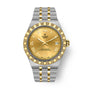 Two-tone stainless steel and gold watch with champagne dial, Roman numerals, date window, and fluted bezel.