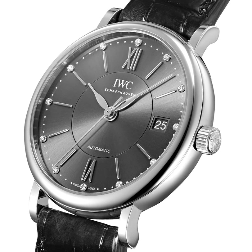 A close-up of a silver IWC Schaffhausen Portofino Chronograph with a black leather strap, featuring a black dial, Roman numeral hour markers, chronograph subdials, and automatic movement.