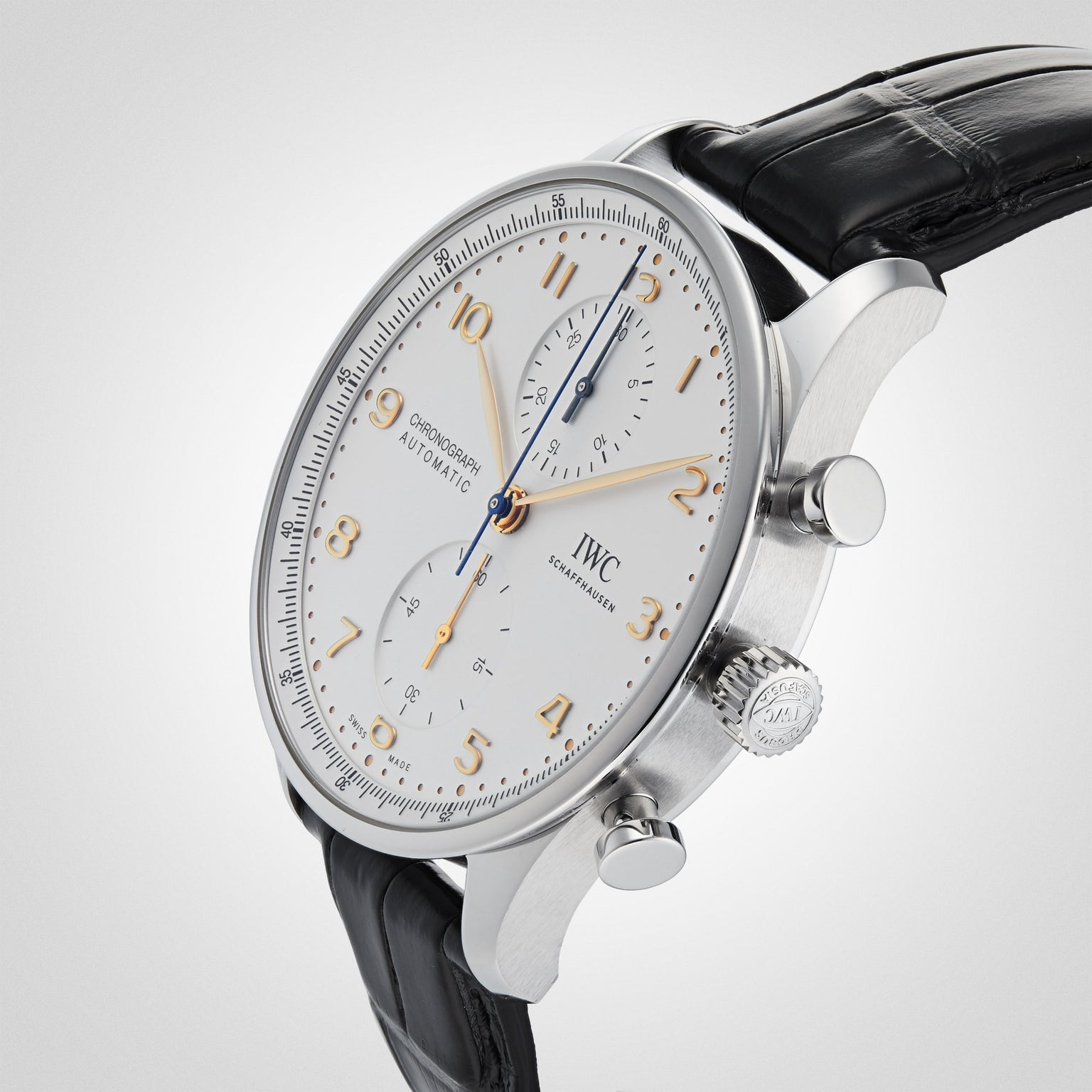 An IWC Schaffhausen Portugieser Chronograph wristwatch with a white dial, gold numerals, black leather strap, and stainless steel case is shown at an angle on a light background.