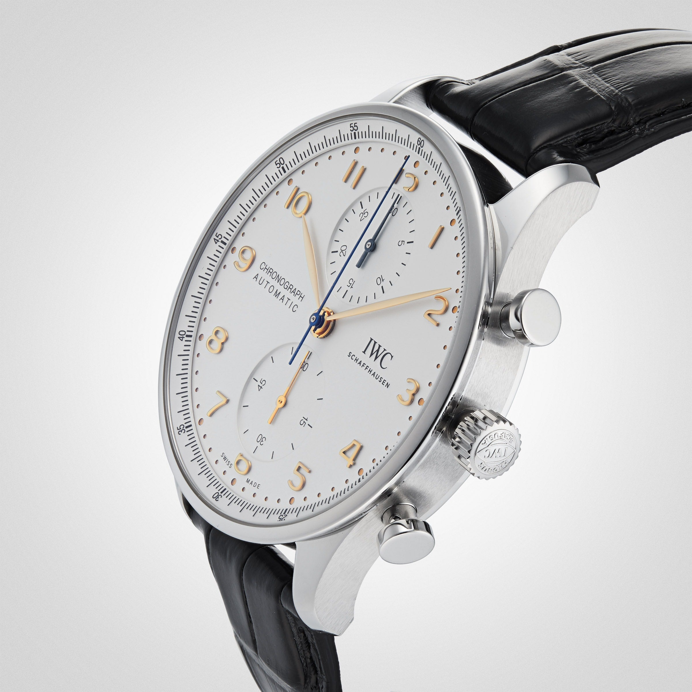 An IWC Schaffhausen Portugieser Chronograph wristwatch with a white dial, gold numerals, black leather strap, and stainless steel case is shown at an angle on a light background.