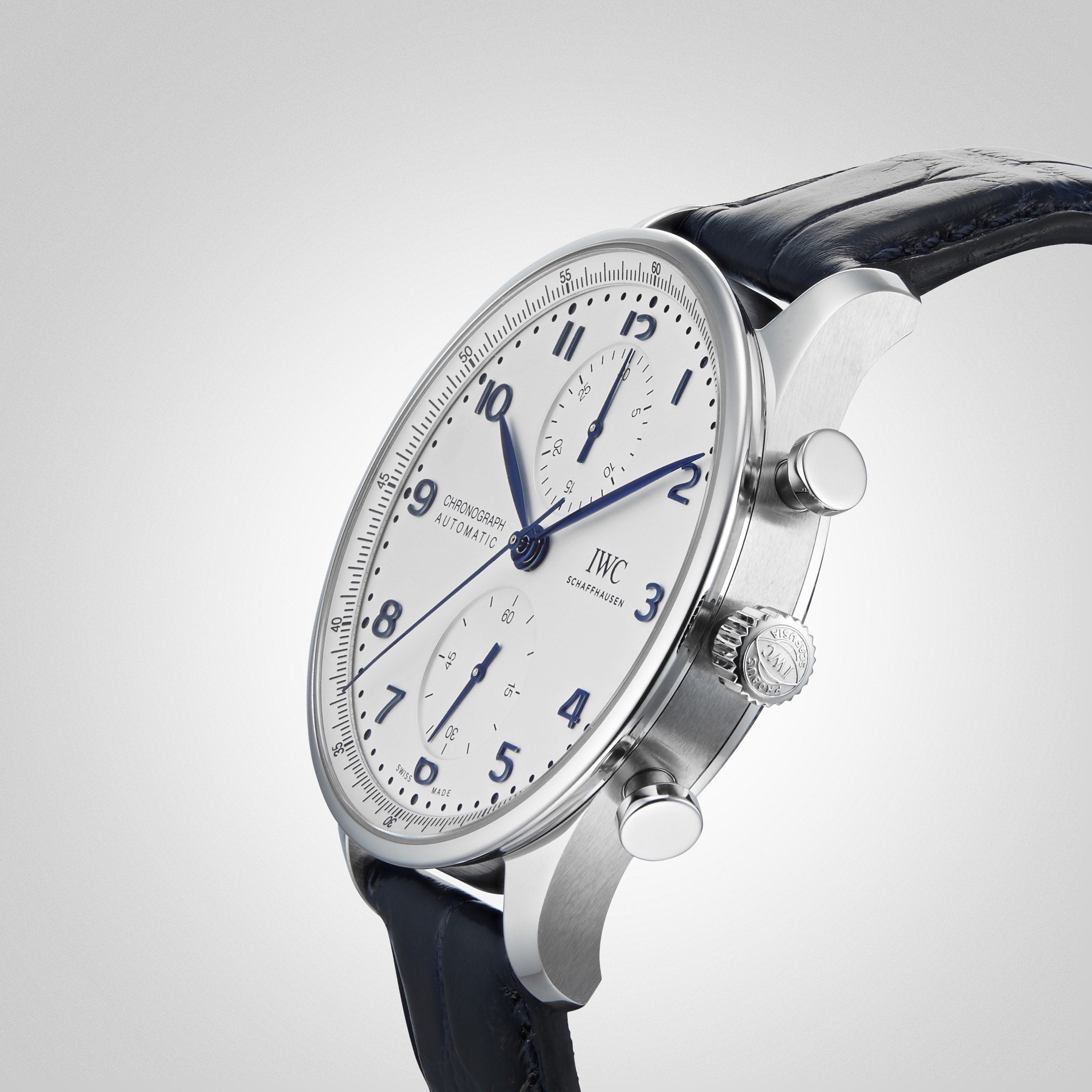 An IWC Schaffhausen Portugieser Chronograph wristwatch with a stainless steel case, white dial, blue hands and numerals, two subdials, and a black leather strap, displayed at an angle on a light grey background.