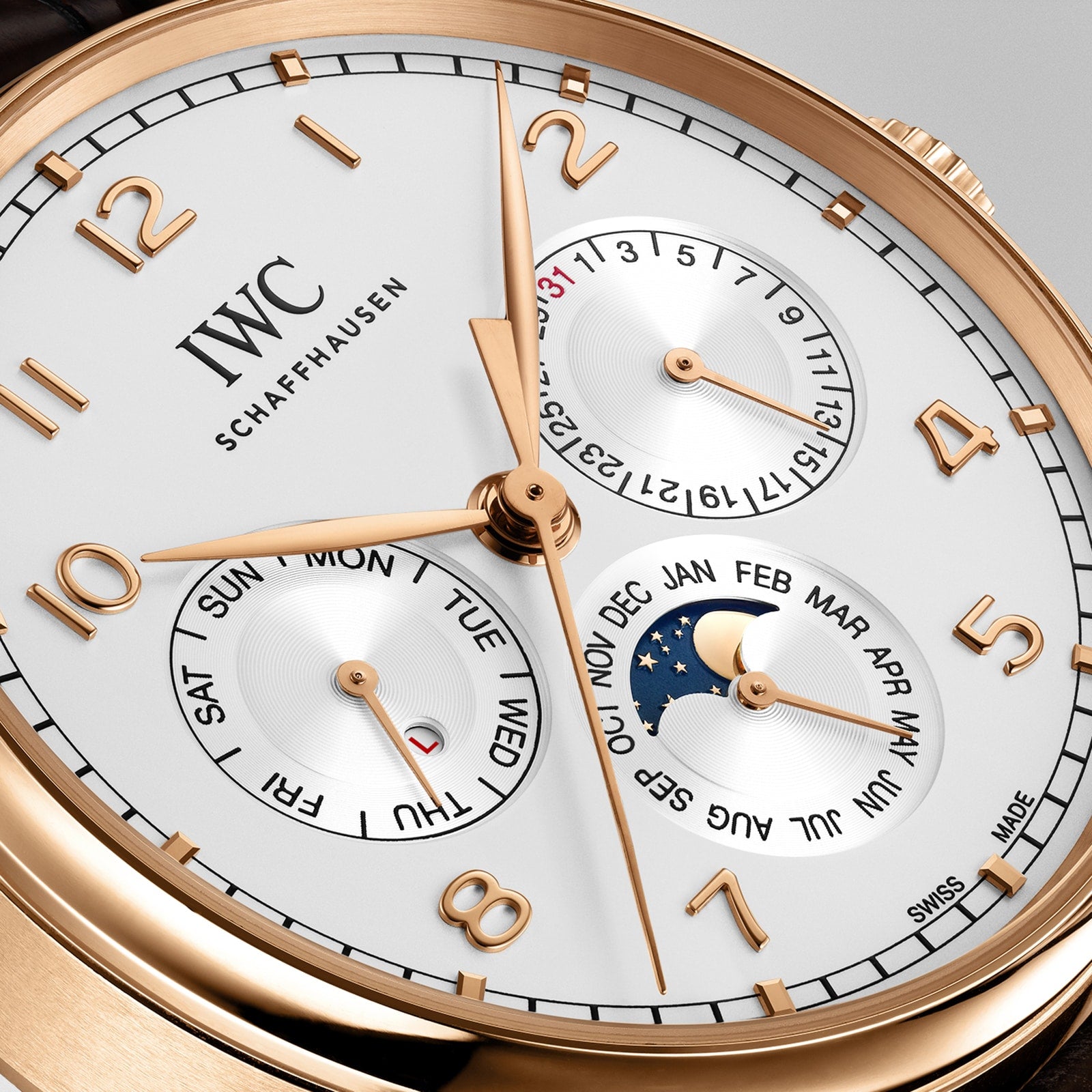 Close-up of the IWC Schaffhausen Portugieser Perpetual Calendar 42, featuring gold hands, moon phase subdials, and perpetual calendar functions in an 18ct gold case with gold hour markers against a white background.