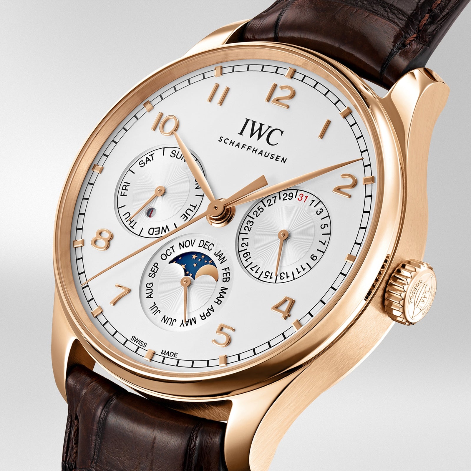 The IWC Schaffhausen Portugieser Perpetual Calendar 42 features a white dial, brown leather strap, 18ct gold case, gold hour markers, and subdials showing day, date, month, moon phase, and perpetual calendar functions.