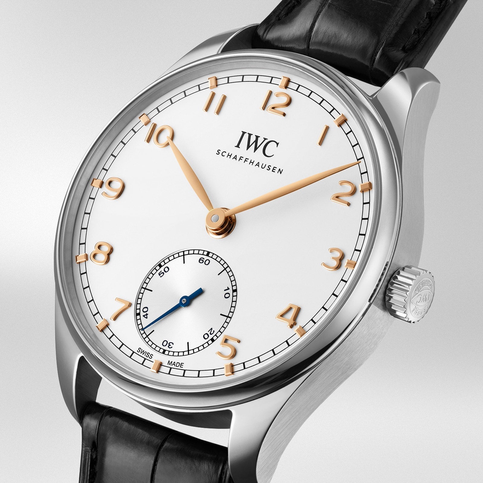 A silver IWC Schaffhausen Portugieser Automatic 40 wristwatch with a white dial, gold hour markers and hands, small seconds subdial at 6 o’clock, and black leather strap.