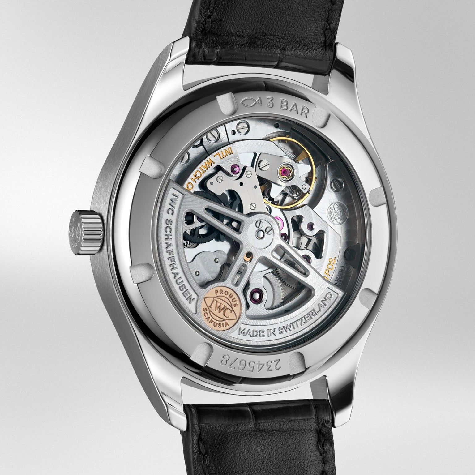 A close-up of the Portugieser Automatic 40 by IWC Schaffhausen shows its inner mechanics—including the IWC-made movement—through a transparent case back with visible metal parts and detailed engravings.