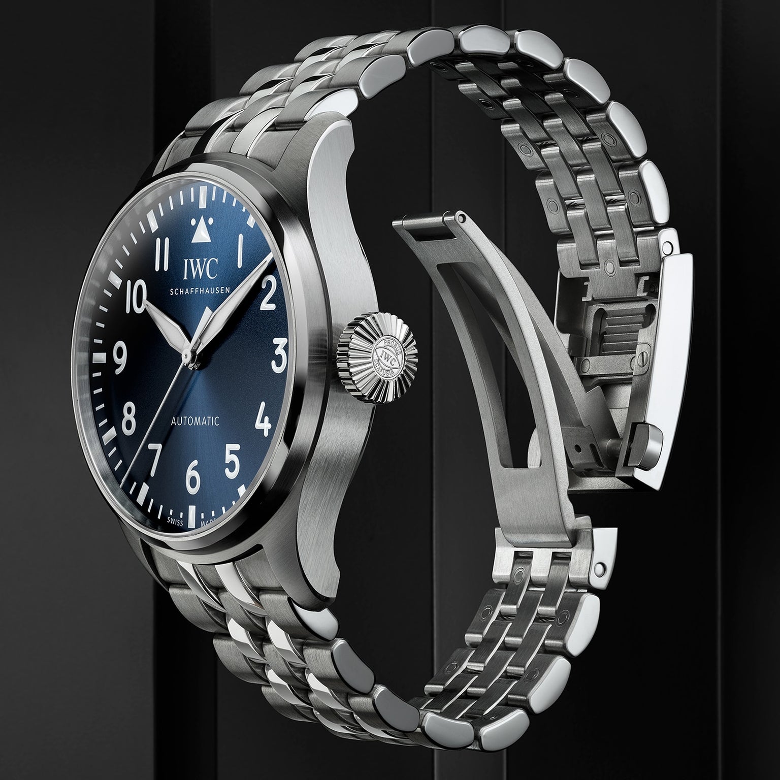 The IWC Schaffhausen Big Pilots Watch 43 in stainless steel features a blue dial with white numerals, a metal bracelet, and the iconic Pilot’s Watches design, showcased against a dark background.