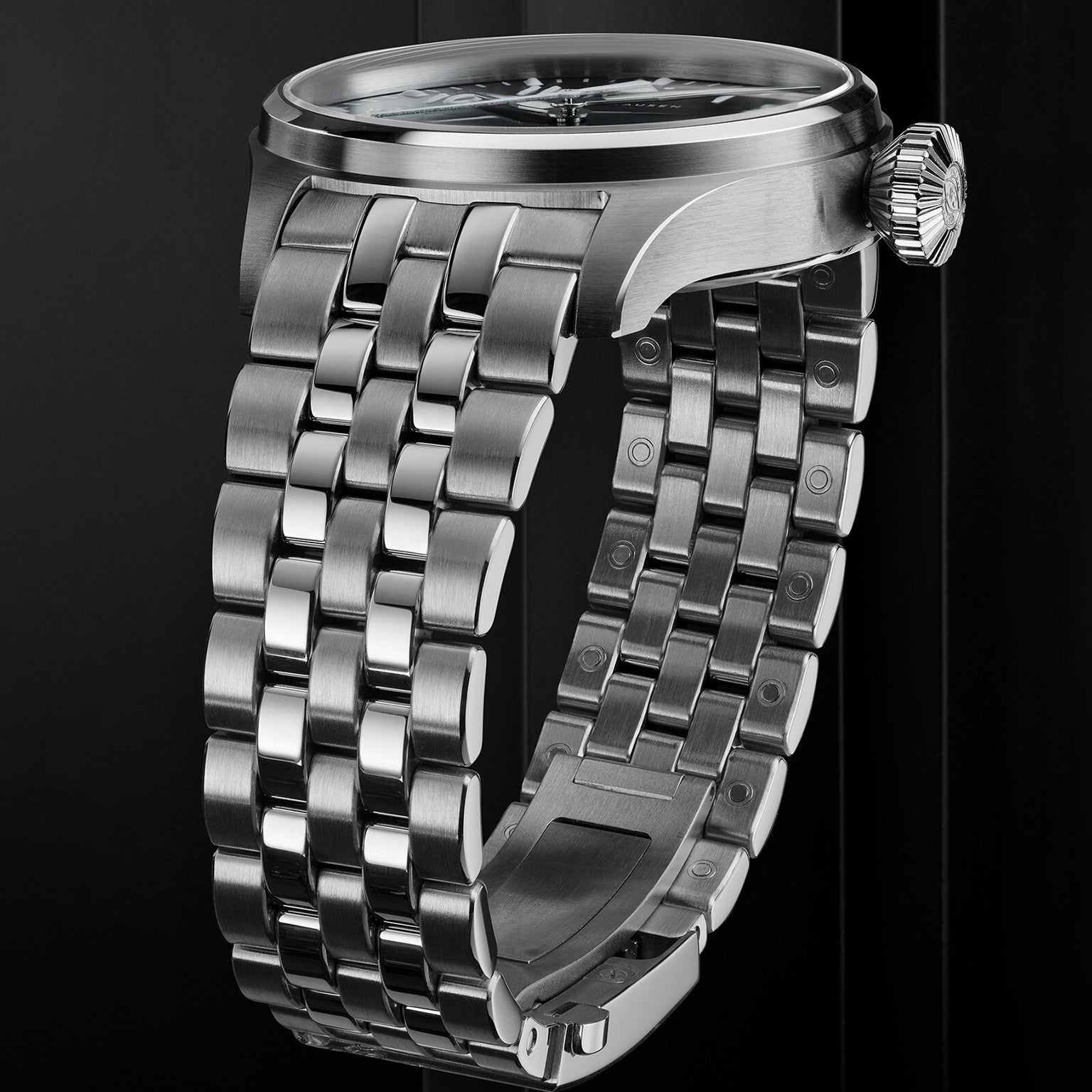 Close-up of IWC Schaffhausens Big Pilots Watch 43, featuring a stainless steel case, polished multi-link bracelet, and prominent crown—an iconic timepiece inspired by classic Pilots Watches, set against a dark background.