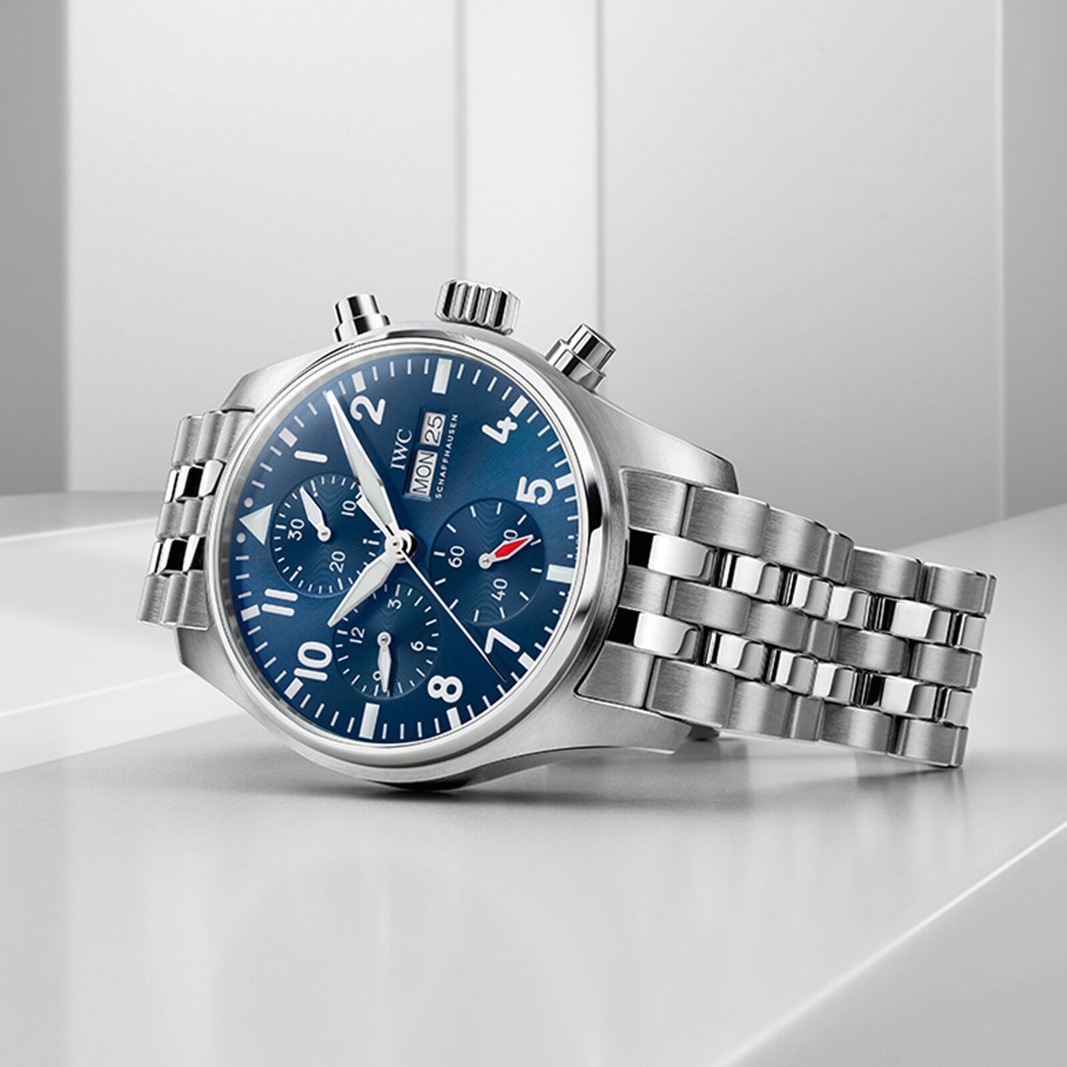 The IWC Schaffhausen Pilots Watch Chronograph 41, featuring a blue dial with three subdials and a stainless steel case, rests on a white surface against a white background.